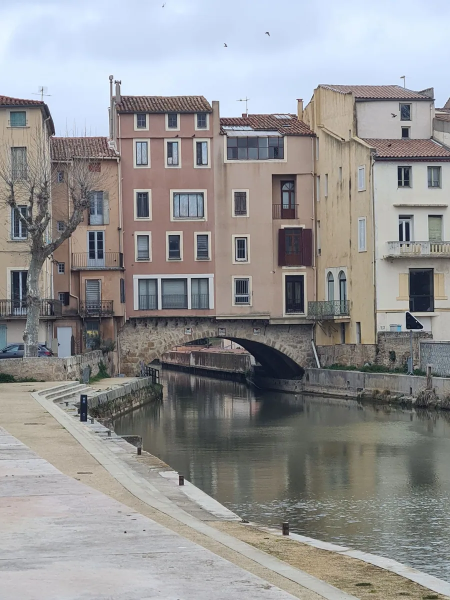 Agence web à Narbonne : un pont historique et des façades colorées au bord du canal à Narbonne