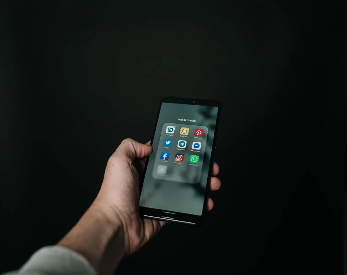 Augmenter sa visibilité entreprise : main tenant un smartphone pour consulter les réseaux sociaux