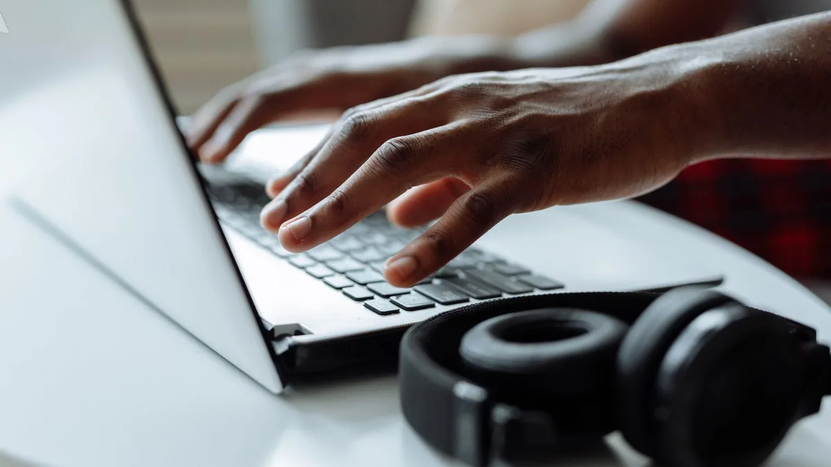 avantages e-learning : mains tapant sur un ordinateur portable à côté d'un casque audio