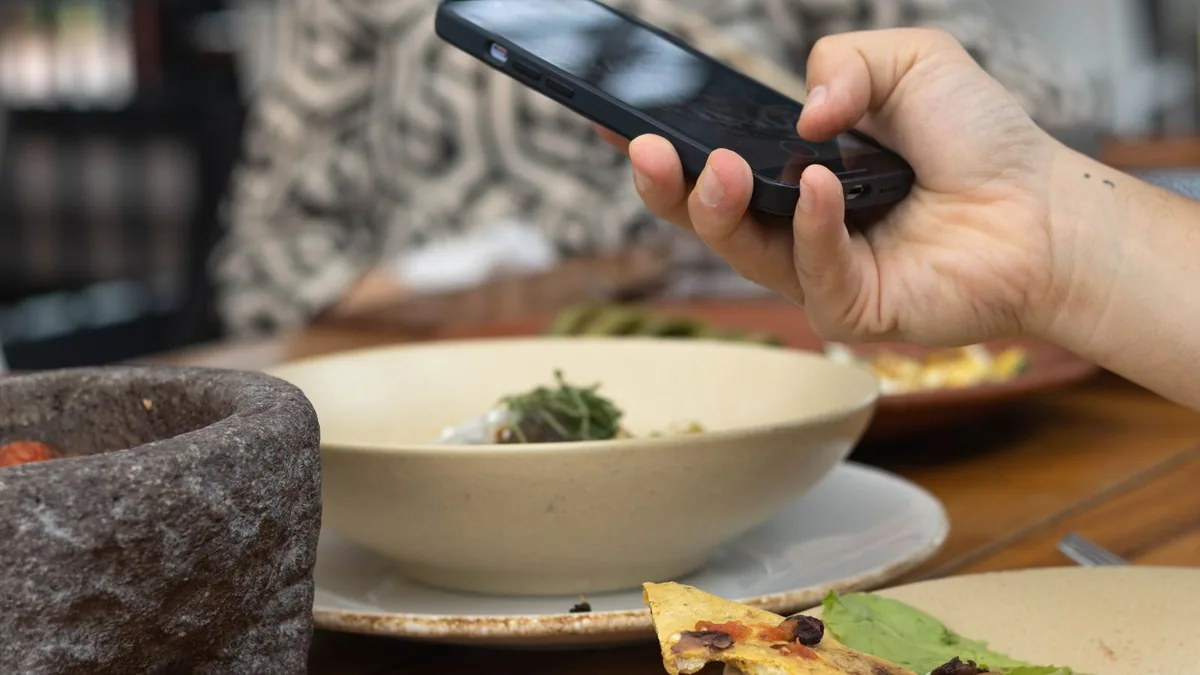 Booster Instagram : une main photographie un plat avec un smartphone pour une publication