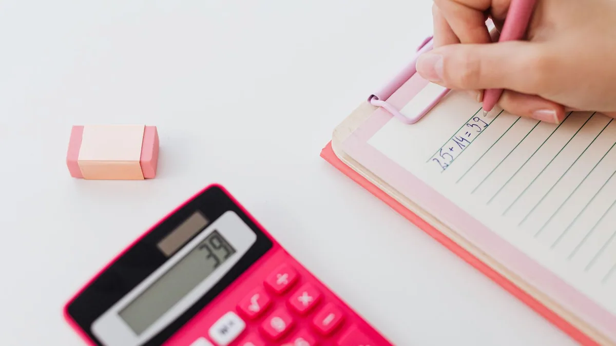 calcul DSO : personne notant des montants à côté d'une calculatrice
