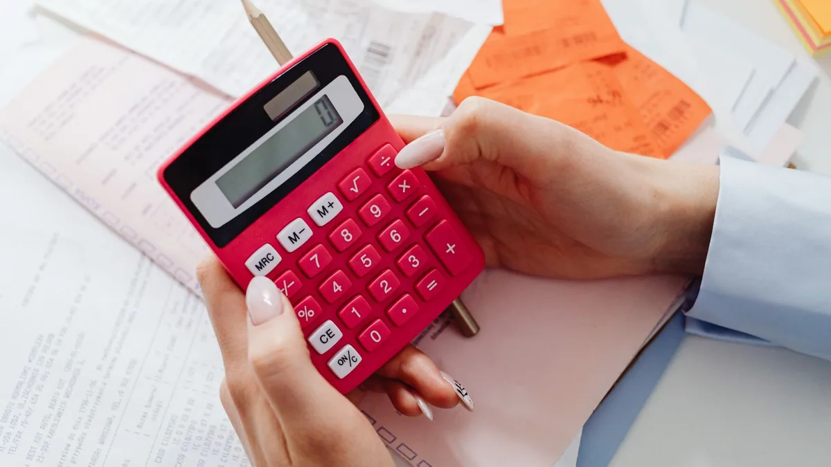 calcul des heures supplémentaires : gros plan sur une main utilisant une calculatrice