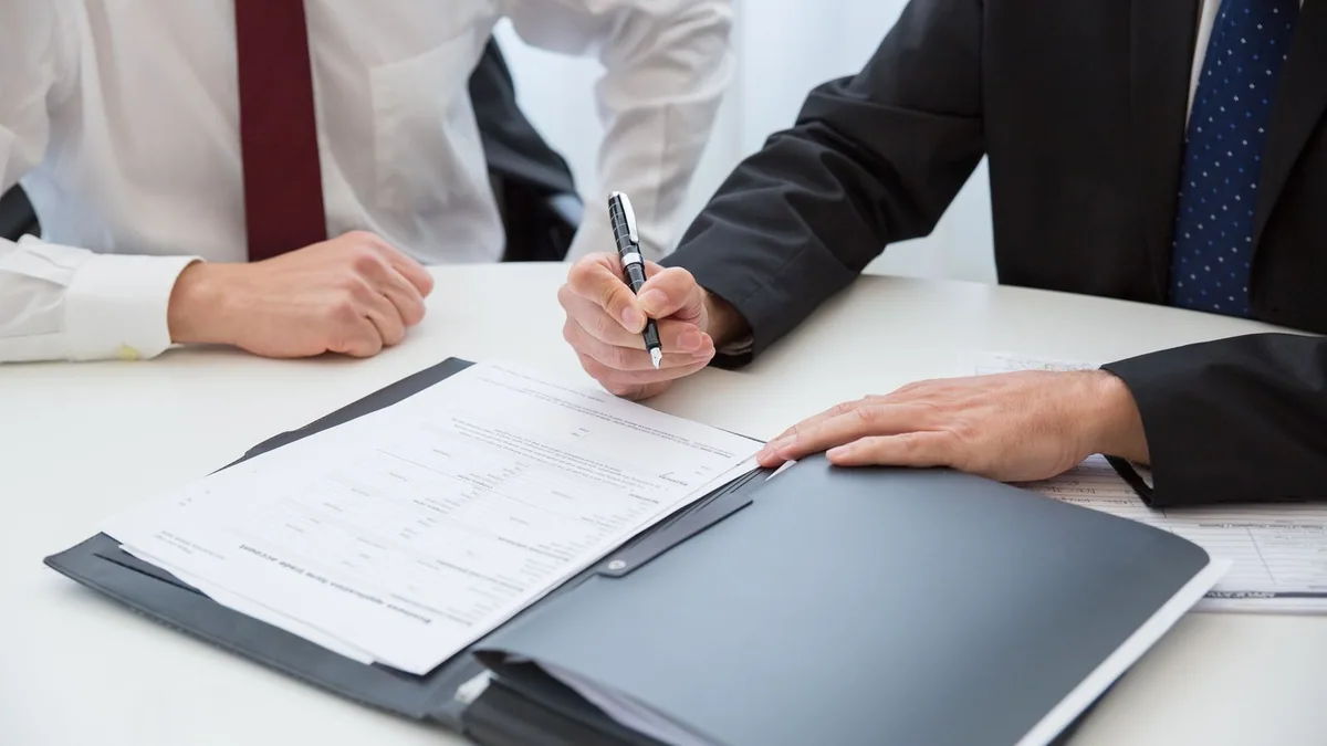 closing commercial : un professionnel tient un stylo près des documents prêts à être signés