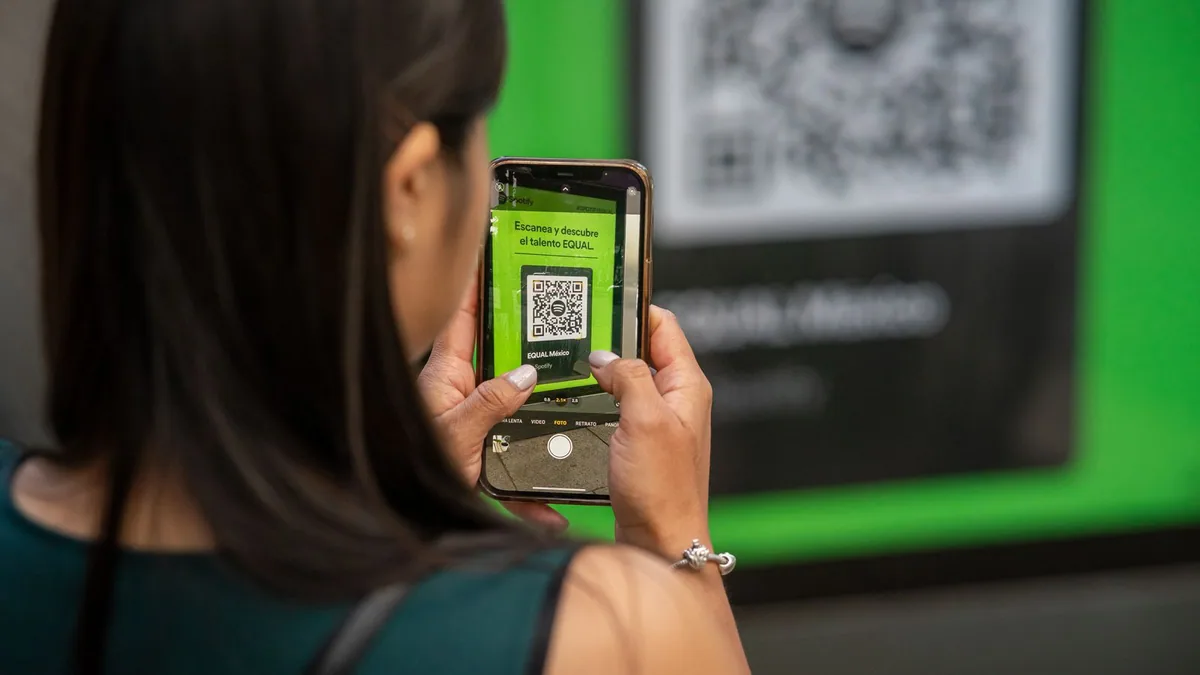 communication print et web : une femme scanne un QR code avec son smartphone