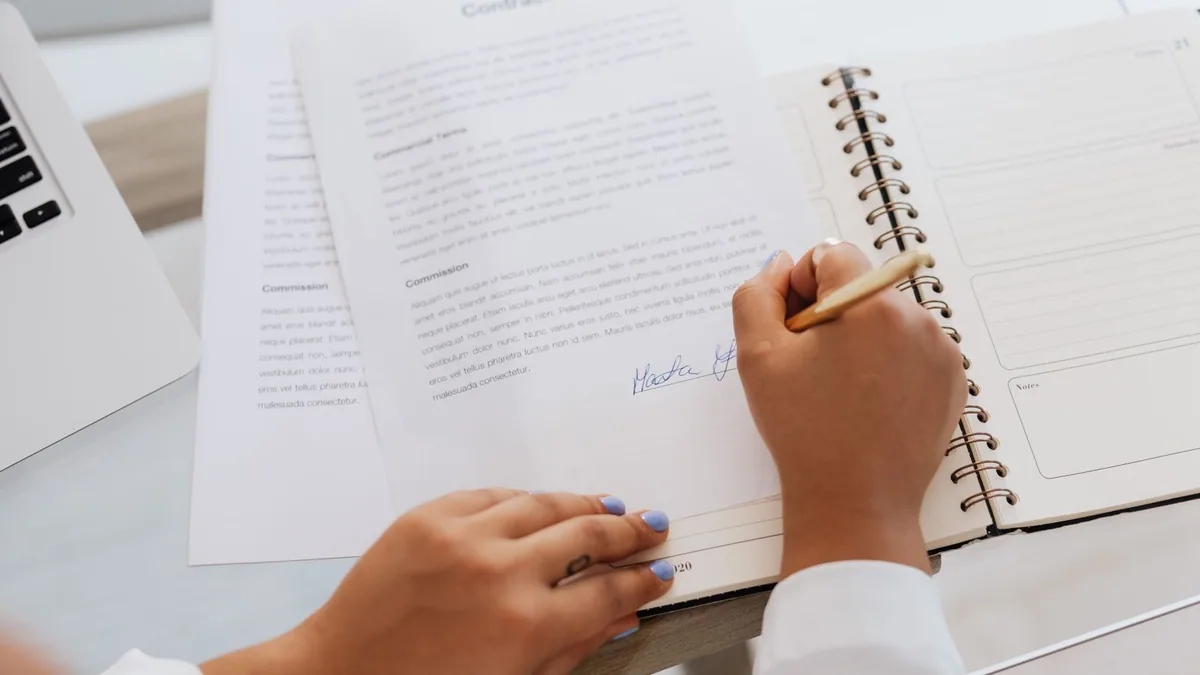 contrat de prestation de service : une personne signe un contrat à son bureau