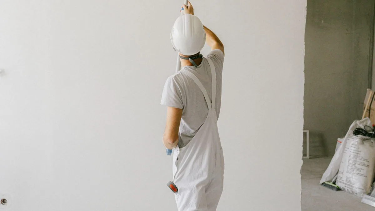 créer une entreprise de peinture en bâtiment : un peintre applique de la peinture au rouleau sur un mur