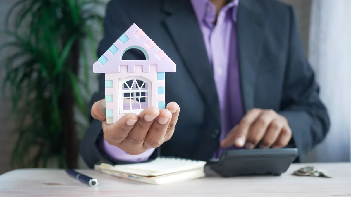 créer une SCI : une personne tient une maquette de maison dans ses mains