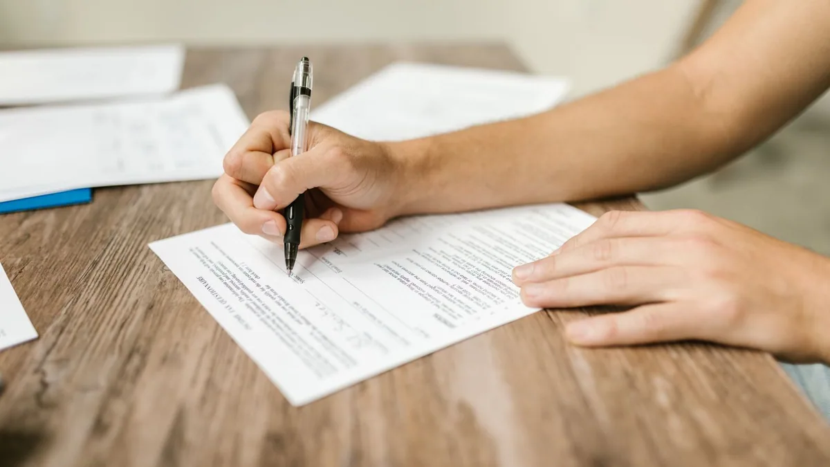 Déclaration de non condamnation : personne remplissant un formulaire au stylo
