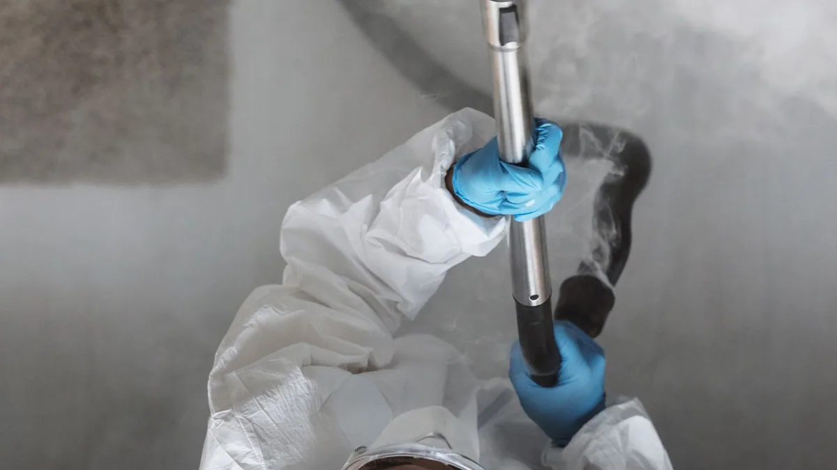 désinsectisation : technicien en tenue de protection diffusant un traitement dans un local
