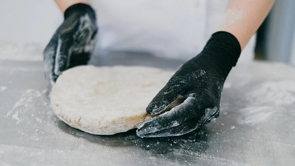 devenir cake designer : pâtissière qui travaille une pâte sur le plan de travail d'un laboratoire