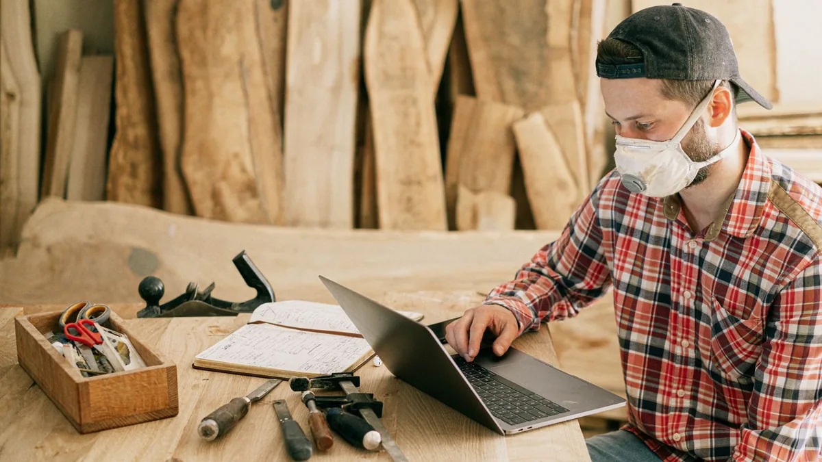 entreprise individuelle : un artisan consulte son ordinateur portable dans son atelier