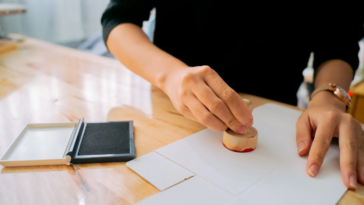 extrait Kbis : main apposant un tampon officiel sur un document