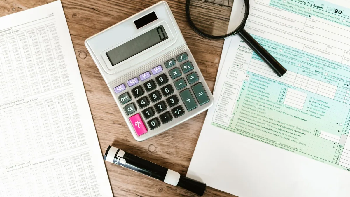gestion comptabilité entreprise : calculatrice et loupe posées sur un bureau pour la révision des comptes