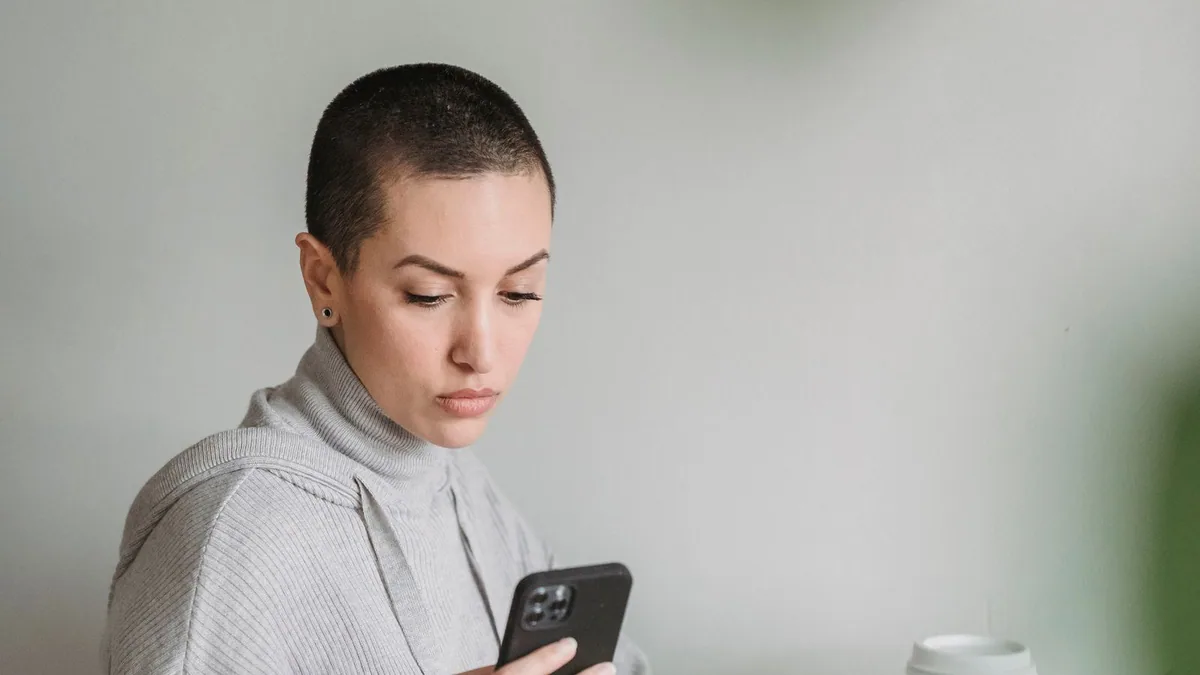 logiciel emailing : une femme prépare une campagne sur son ordinateur avec son smartphone en main