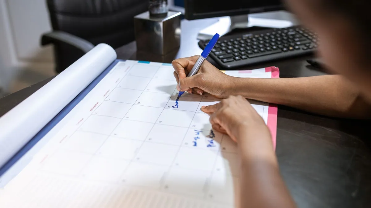 mail de relance client : une personne planifie ses relances sur un calendrier de bureau
