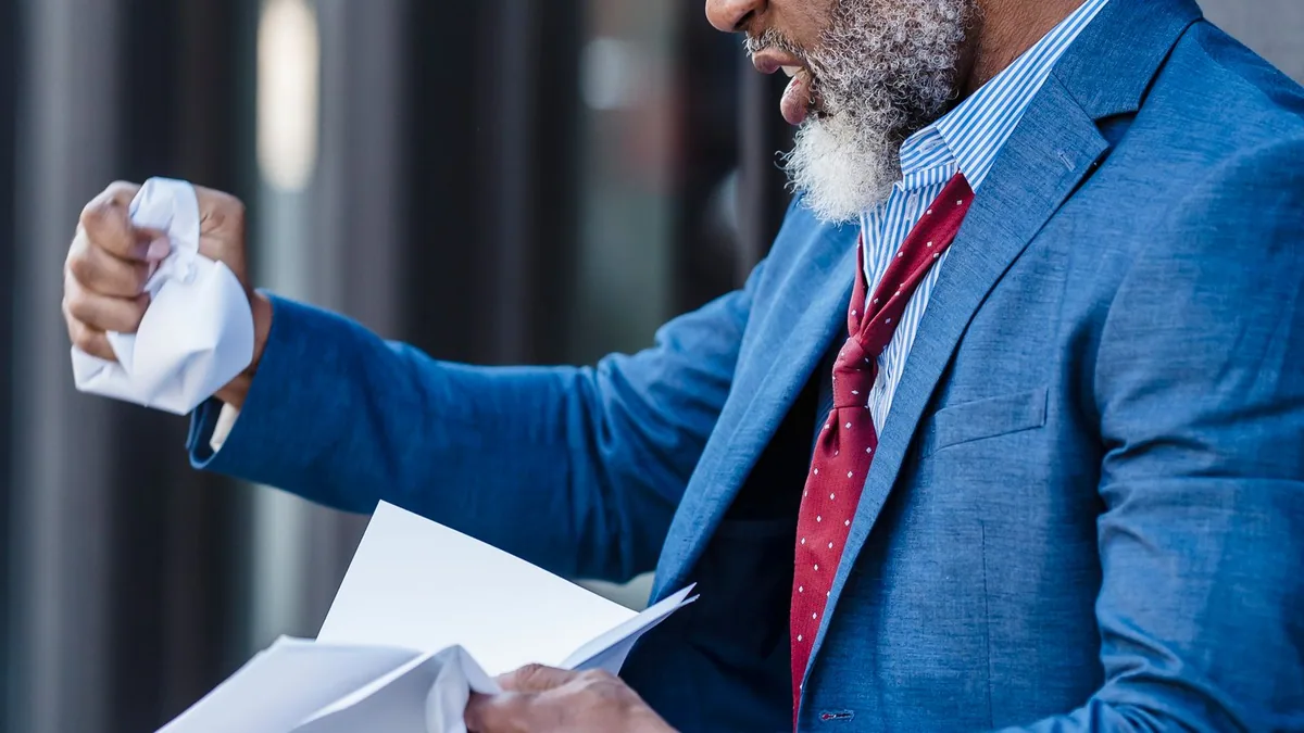 mauvaise image de marque : un homme d'affaires mécontent froisse une feuille de papier