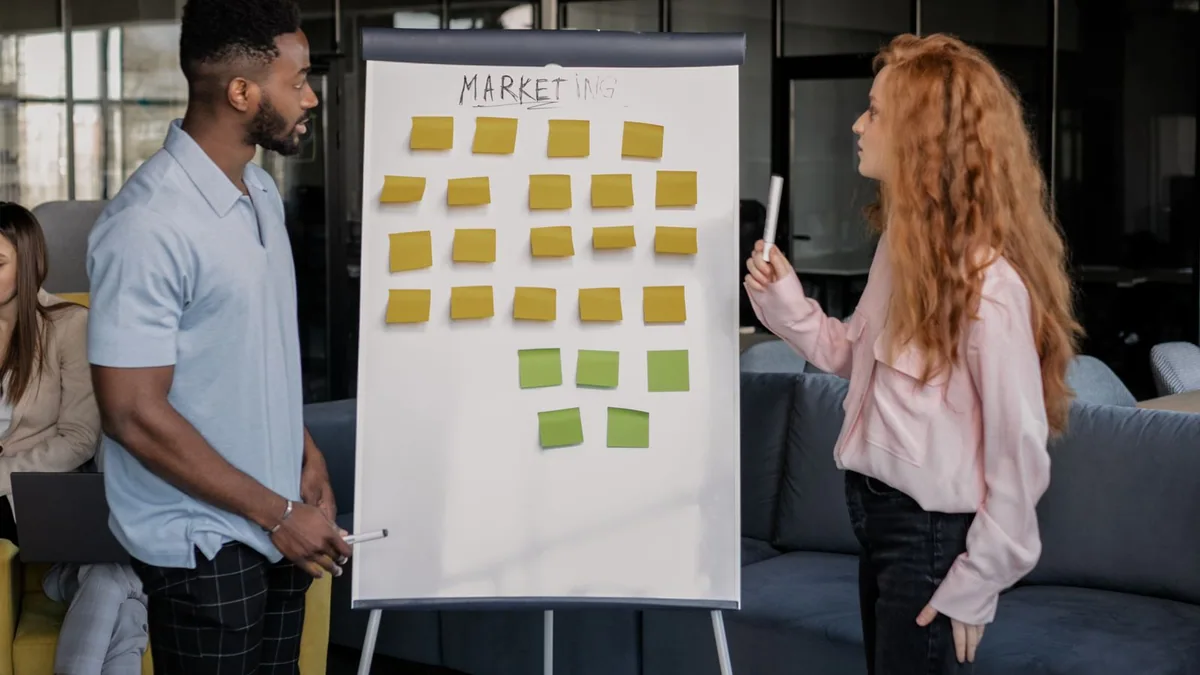 modèle économique : deux personnes construisent un plan d'affaires devant un tableau blanc