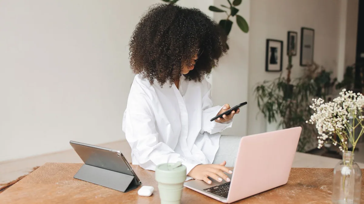 Nom de domaine professionnel : femme utilisant son téléphone et son ordinateur pour son activité