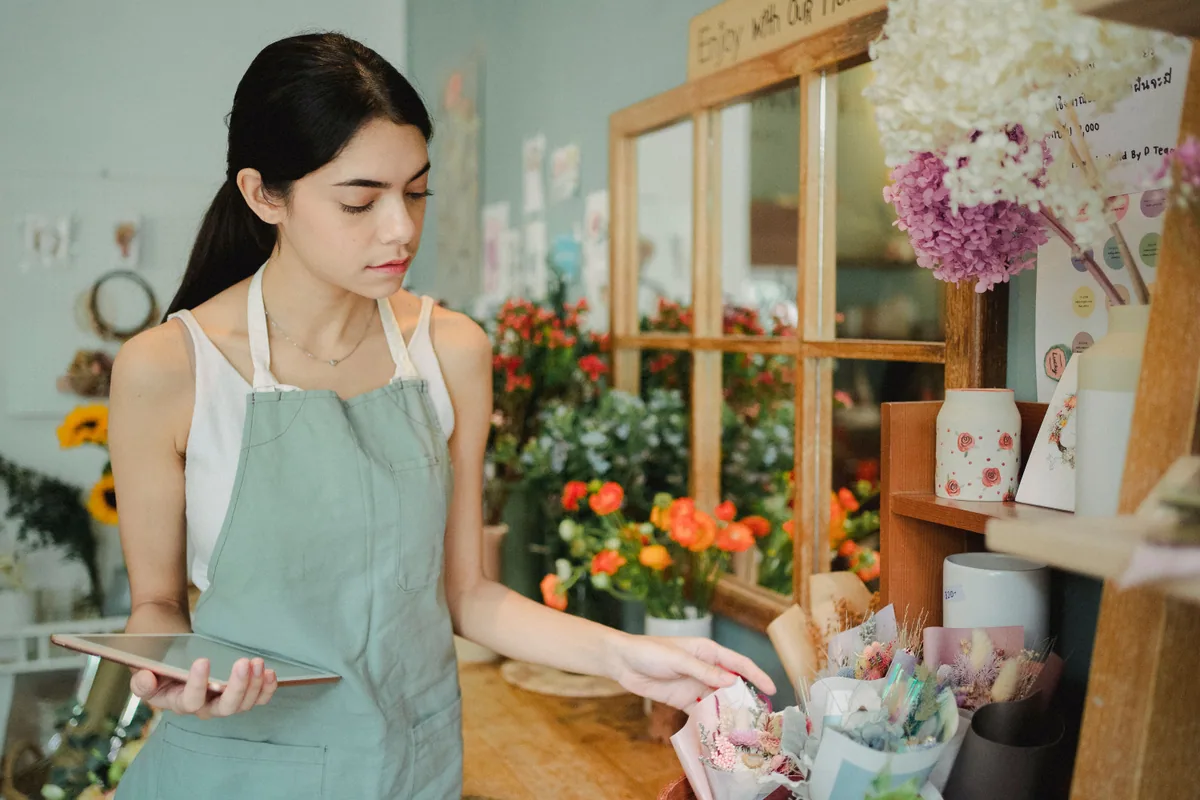 comment promouvoir son entreprise : fleuriste avec une tablette dans sa boutique