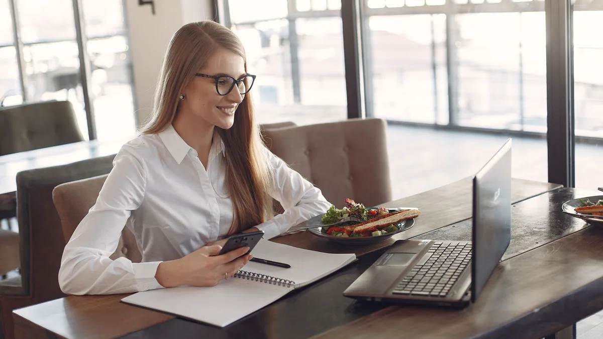 Référencer son entreprise sur Google : entrepreneuse utilisant son smartphone et son ordinateur dans un café