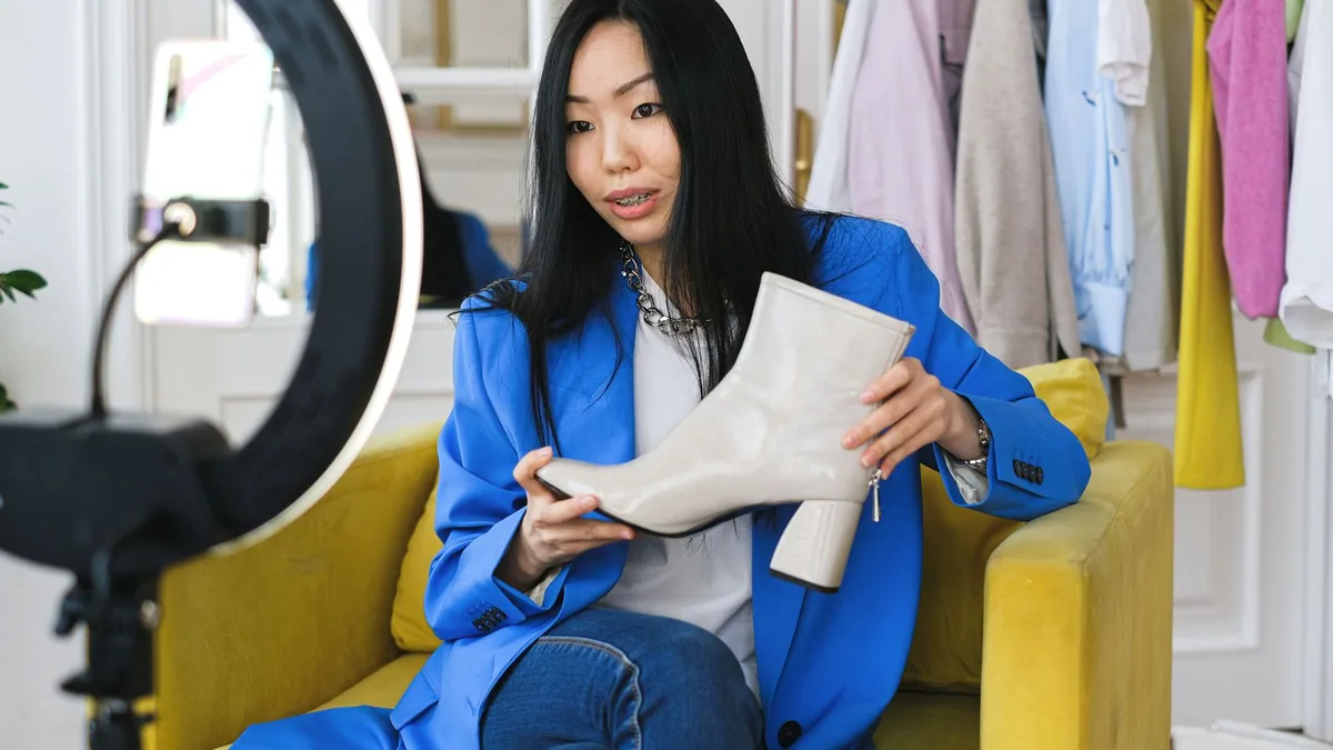 Salaire influenceur : une créatrice présente des chaussures à vendre devant son smartphone