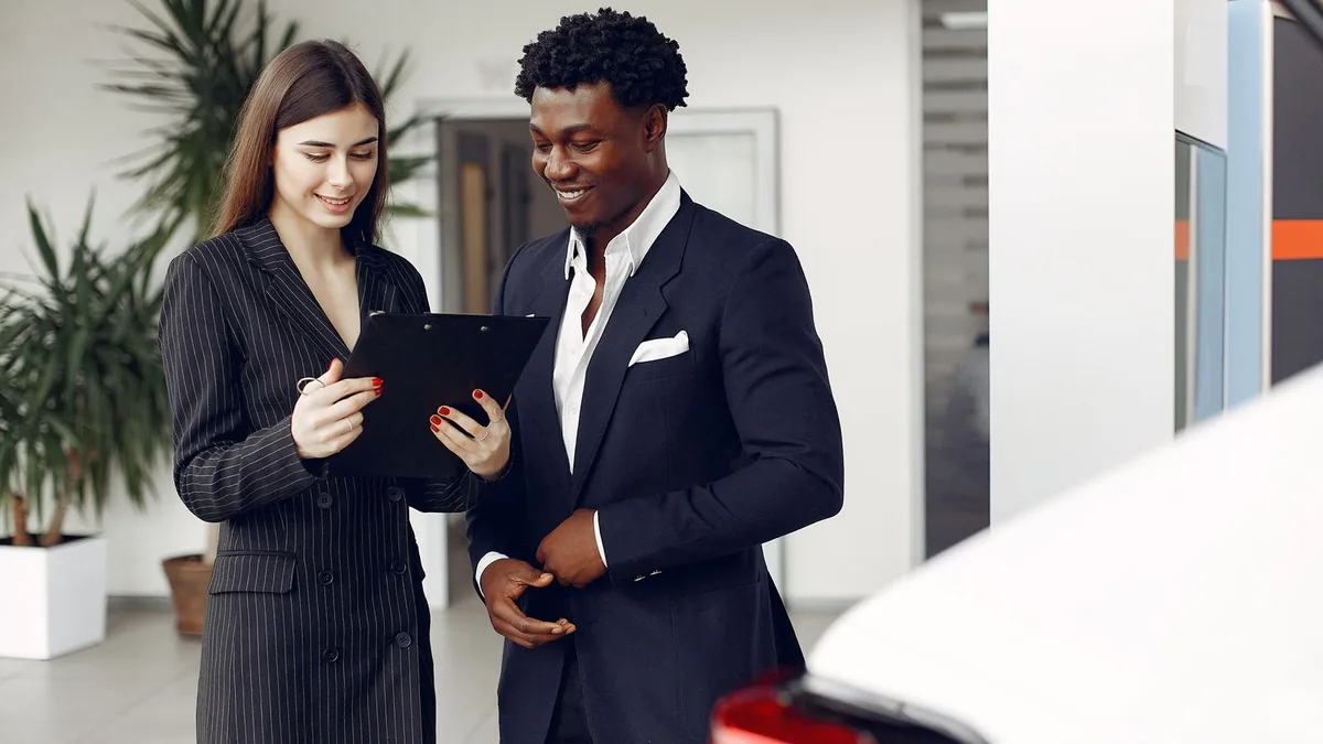 SEO local concession : vendeur automobile et client consultant un document en showroom