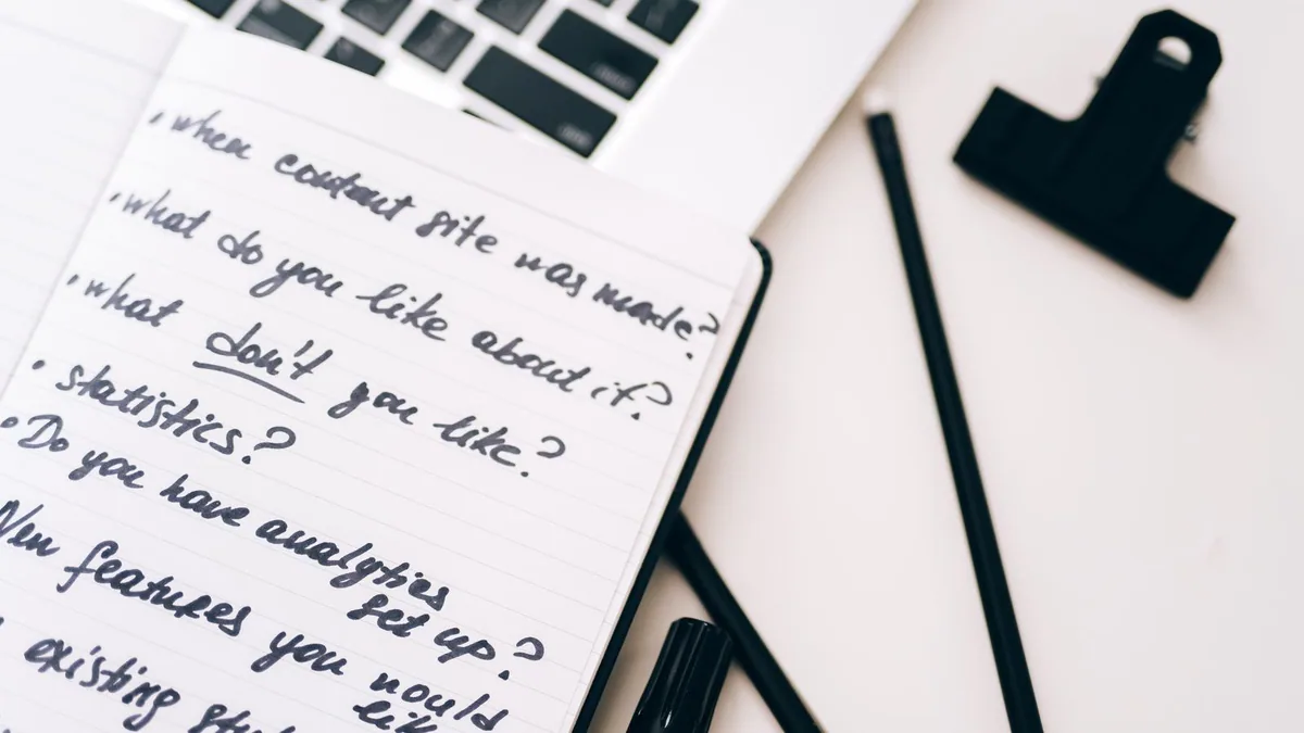 stratégie de contenu seo : carnet de notes manuscrites ouvert à côté d'un ordinateur portable